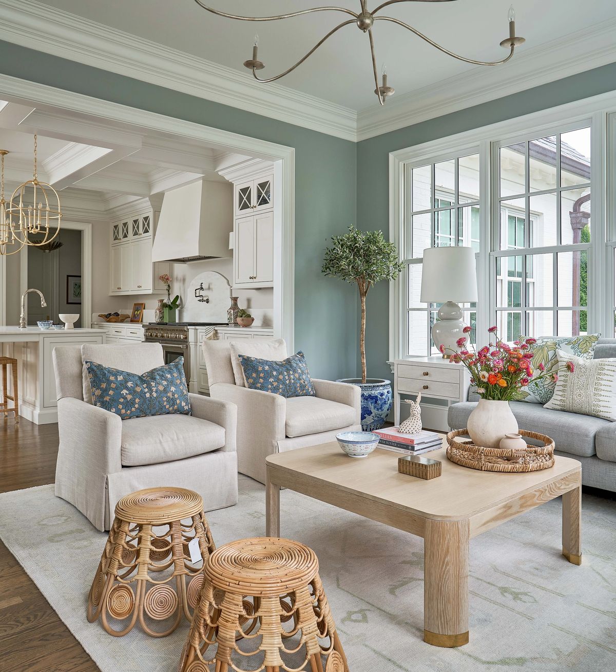 Living room with gray walls, beige sofa, patterned armchairs, coffee table, and large window with natural light.