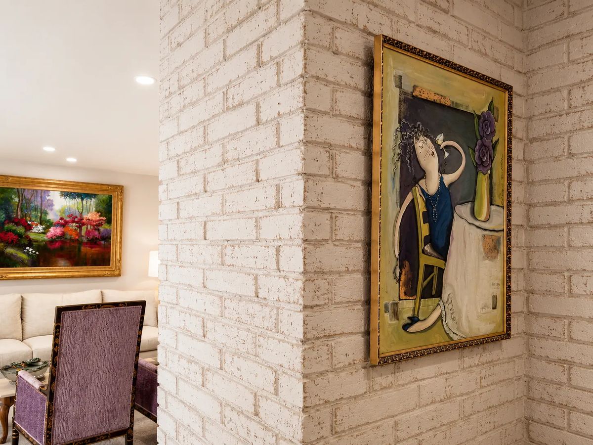 Living room with beige textured wall, paintings, small round table, and purple chair.