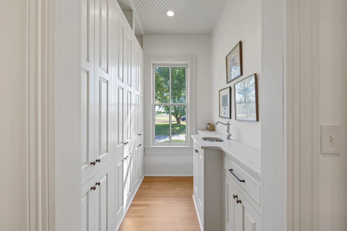 Laundry room with white cabinetry, countertop, stainless steel sink, and a large window