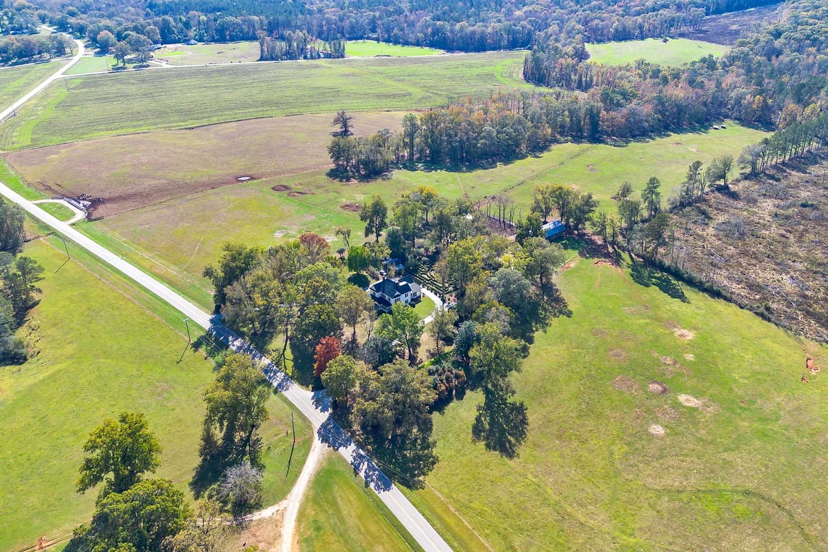 Exterior view of a large property with green lawns, trees, and a winding road.