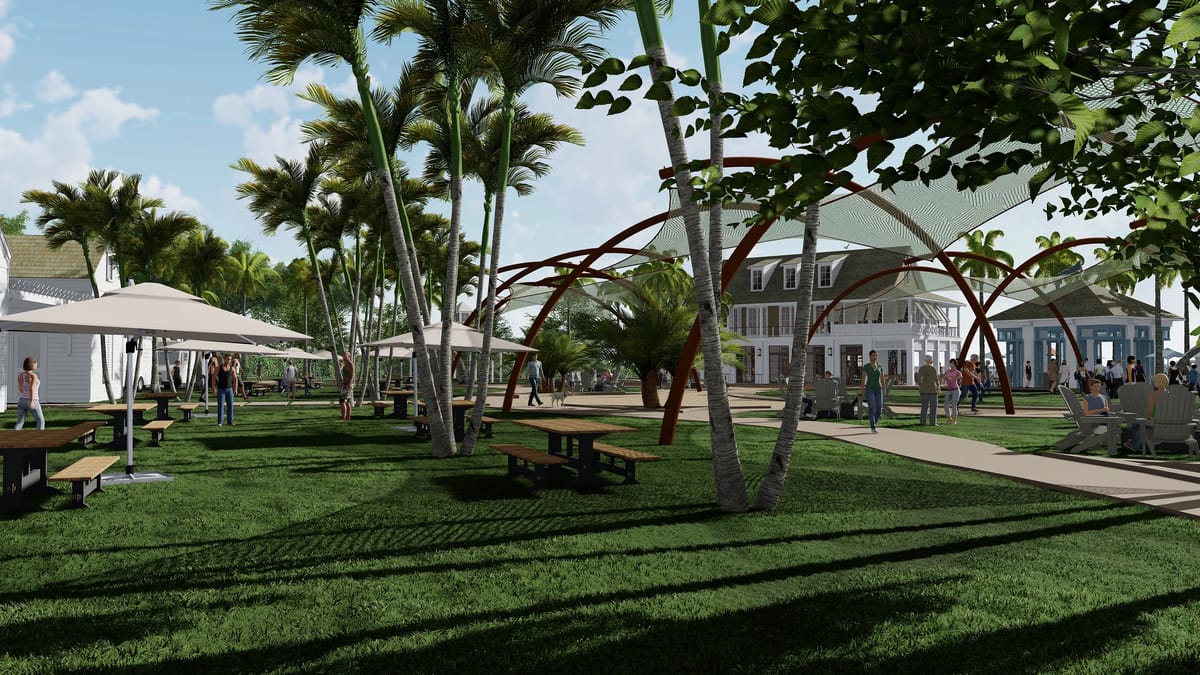 Garden area with grass, palm trees, picnic tables, umbrellas, and seated individuals.