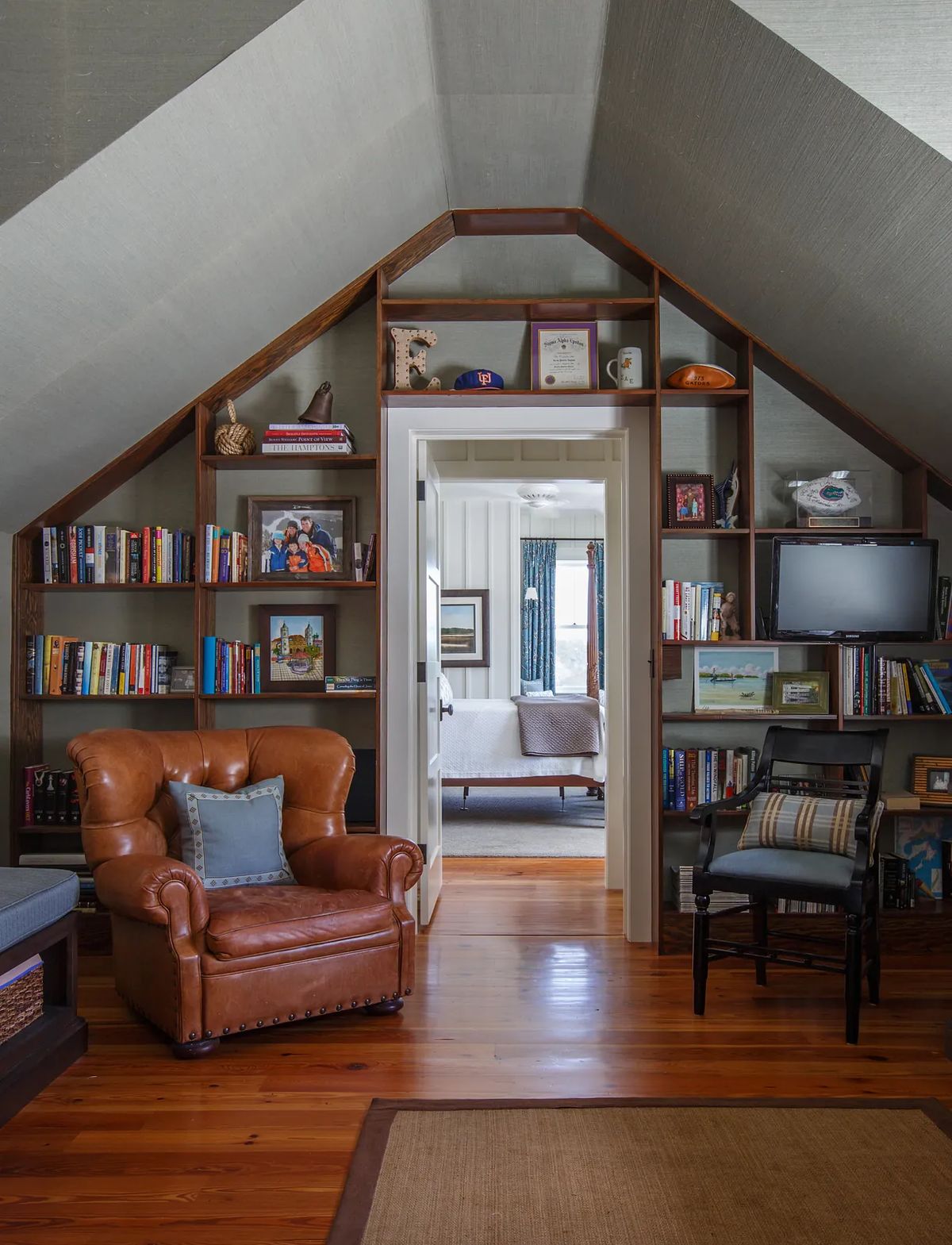 Attic space with brown leather chair, wooden bookshelves, and doorway to another room