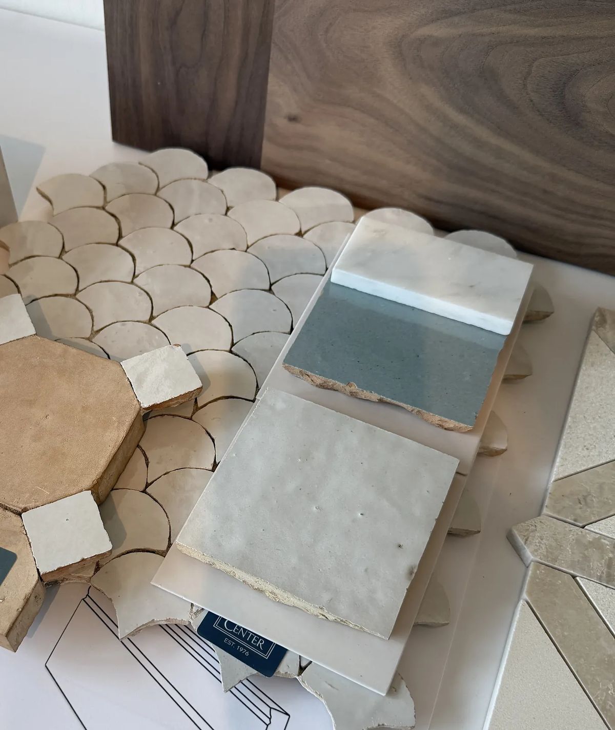 Tile samples including hexagonal, scalloped, and rectangular shapes in neutral and pastel colors with wood veneer.