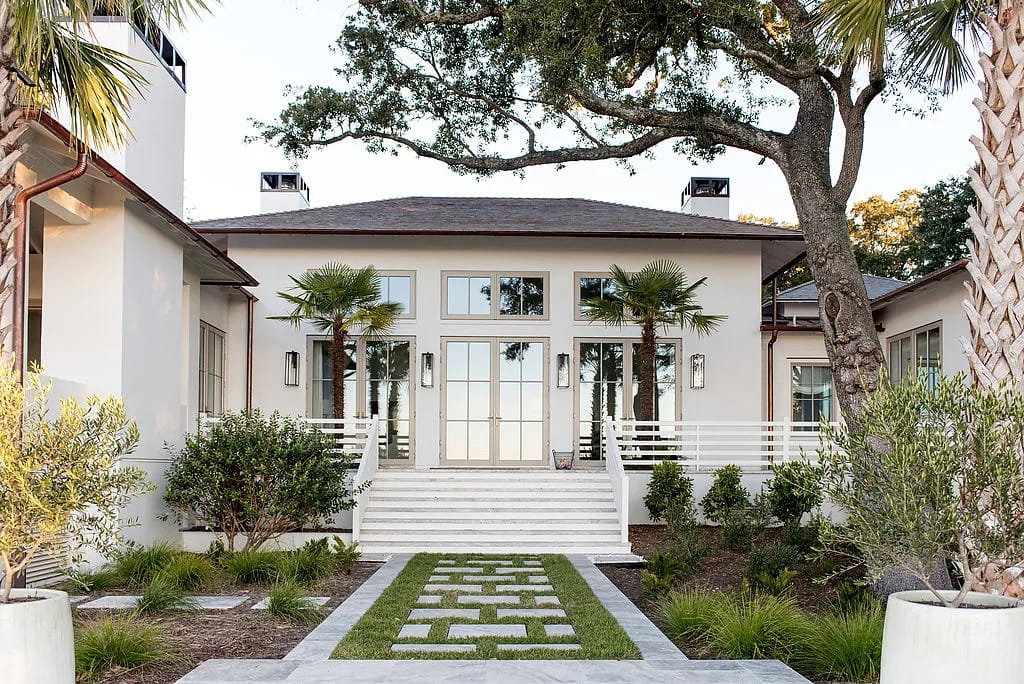 Exterior front view of a house with double doors, large windows, stairs, and palm trees.