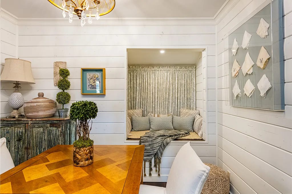 Dining room with wooden table, white chairs, built-in window nook, and decorative wall art.