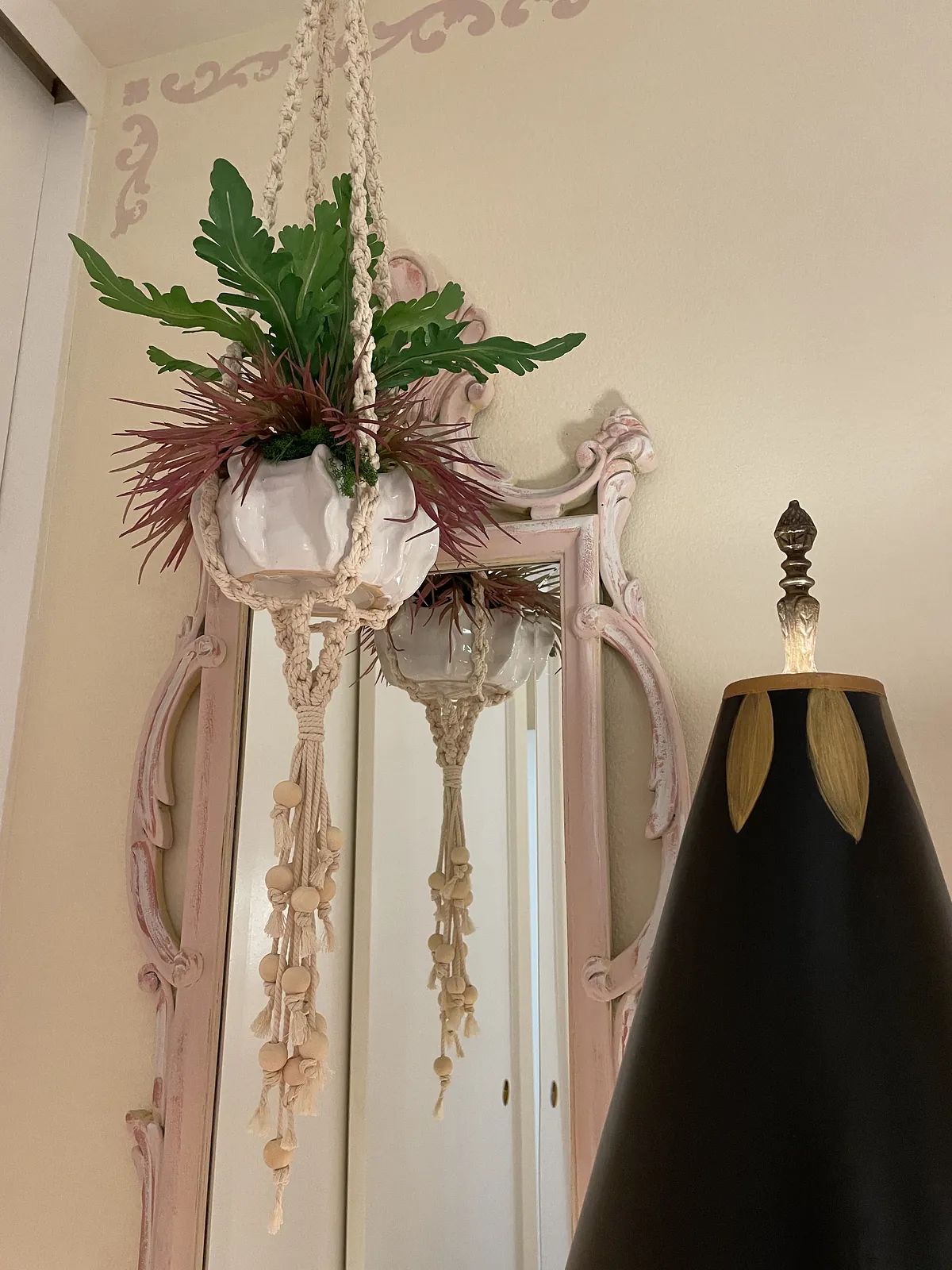 Wall scene with ornate mirror, hanging planter, and black lamp.
