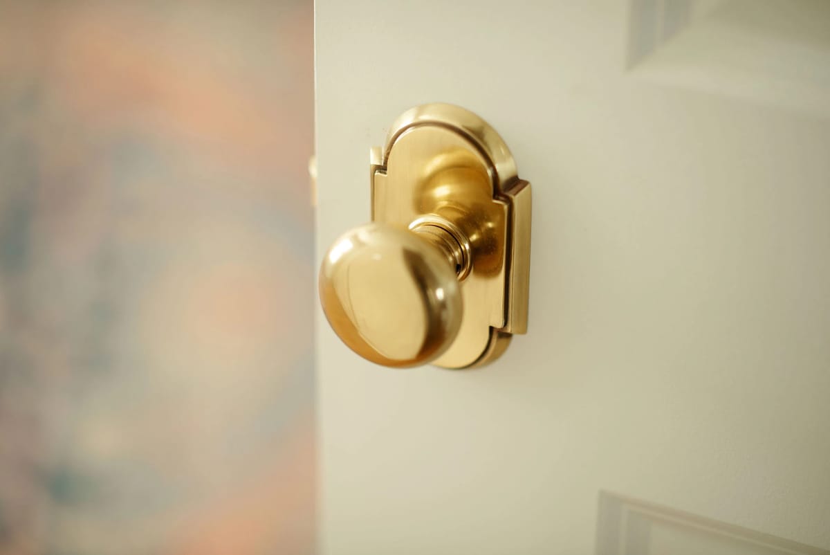 Close-up of a gold doorknob on a white door with a blurred background.