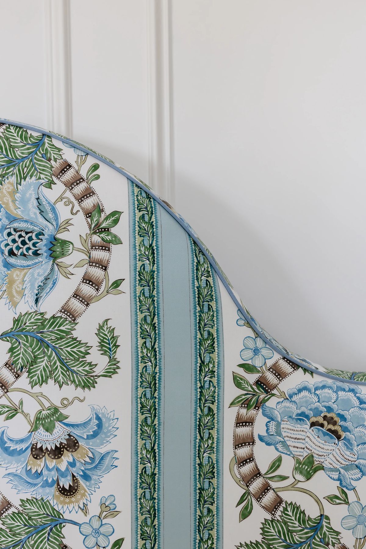 Close-up of patterned fabric with floral designs in blue, green, and cream colors against a white background