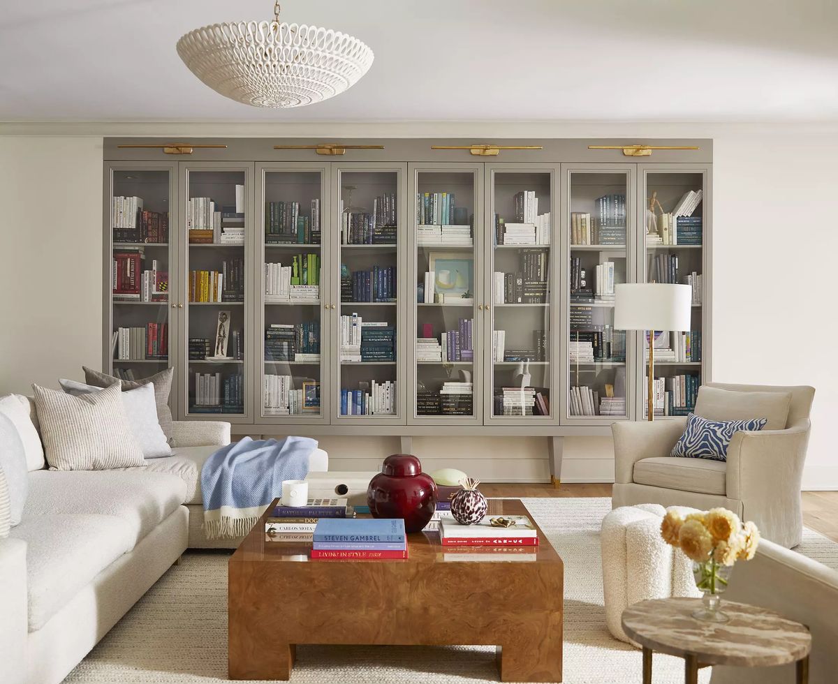 Living room with light sofa, wood coffee table, area rug, built-in bookshelves, and chandelier.