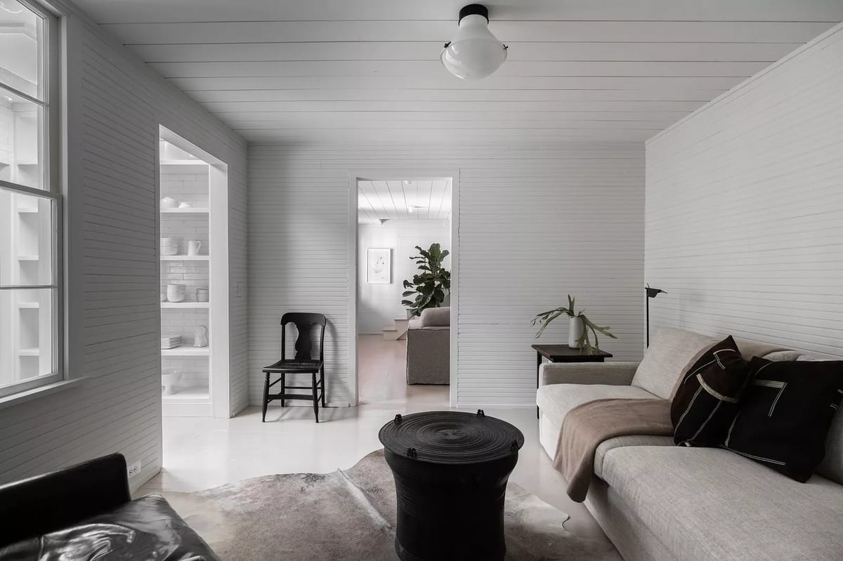 Living room with white sectional sofa, black side table, cowhide rug, and a potted plant with natural light.