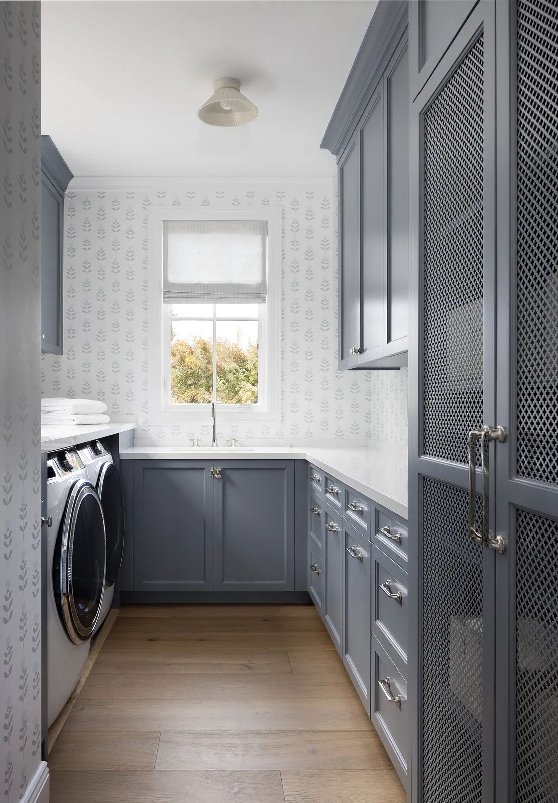 Laundry room with gray cabinetry, white countertop, window, washer, dryer, sink, and wood flooring