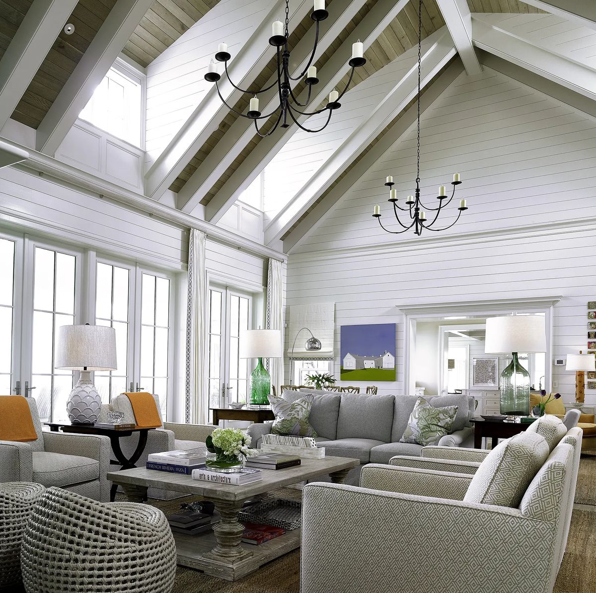 Living room with gray sectional sofa, armchairs, ottomans, coffee table, area rug, and large windows