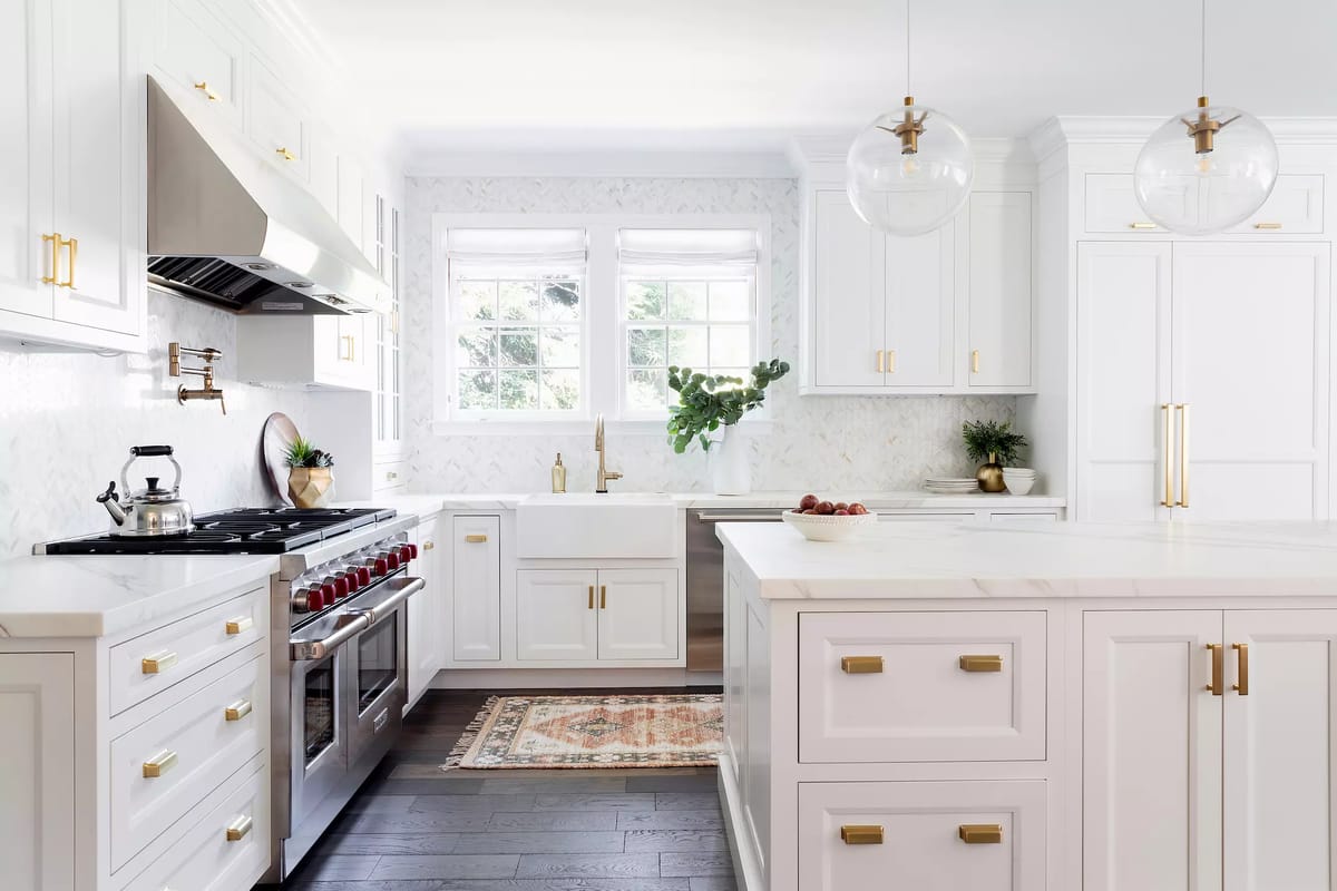 Kitchen with white cabinetry, stainless steel range, marble countertops, farmhouse sink, and pendant lights.