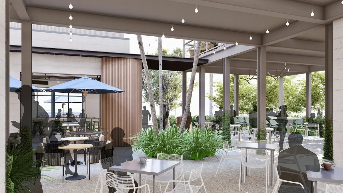 Outdoor patio with light gray tables, white chairs, blue umbrella, and lush green plants.