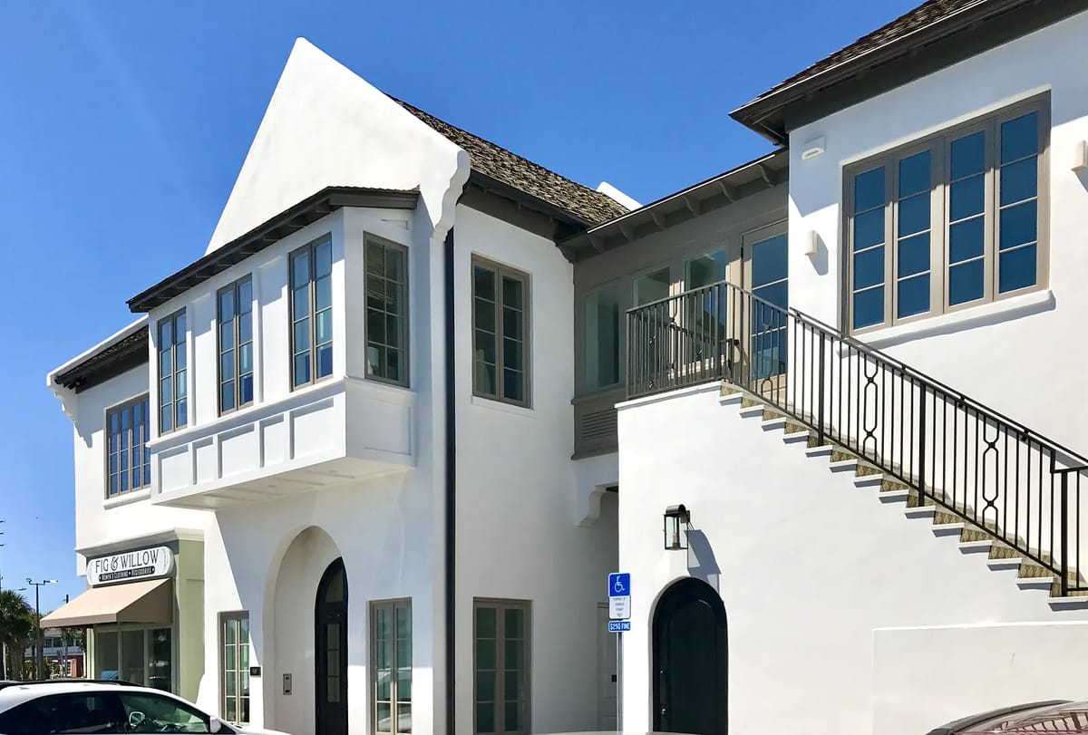 Exterior front view of a white building with large windows and a staircase.