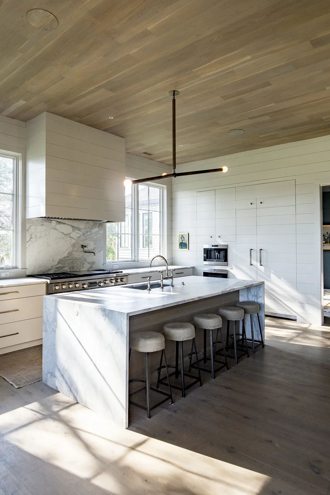 Kitchen with marble island, stainless steel range, white cabinetry, and large windows for natural light