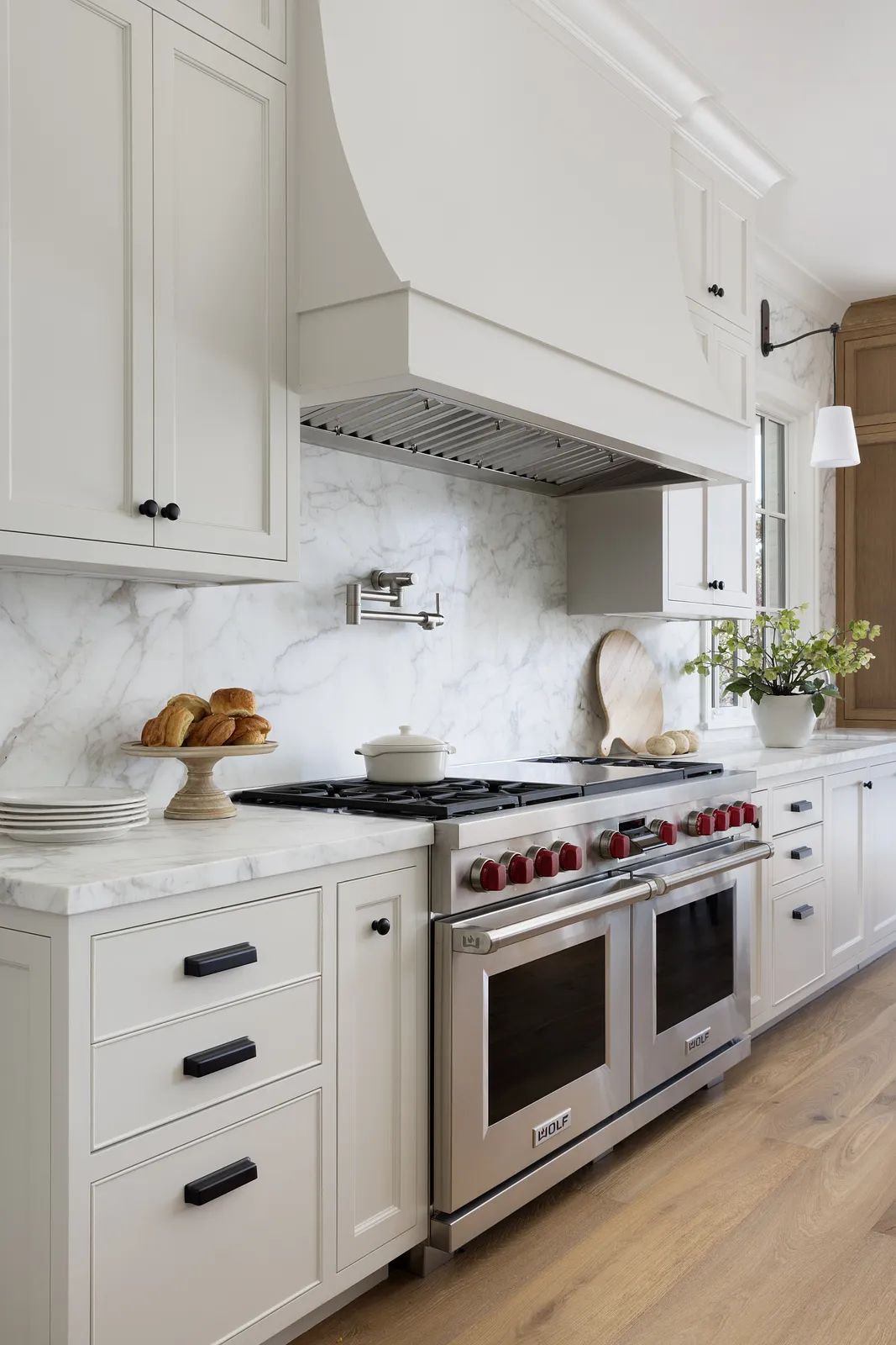 Kitchen with stainless steel range, marble backsplash, wooden cabinetry, and natural light from large windows.