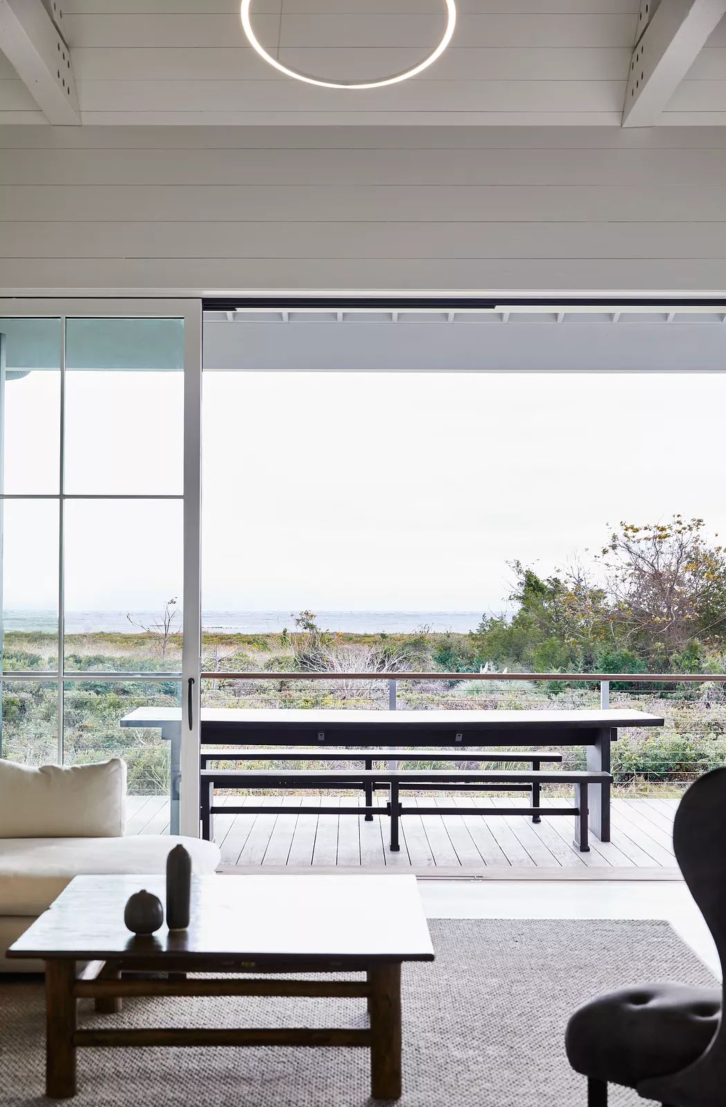 Living room with white sofa, wooden coffee table, and large sliding glass doors to deck