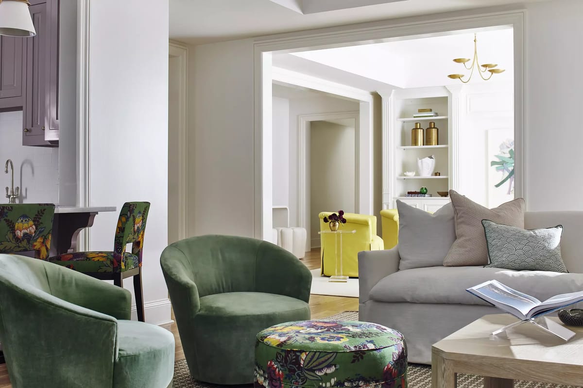 Living room with green accent chairs, gray sofa, wood table, and natural light from adjacent rooms
