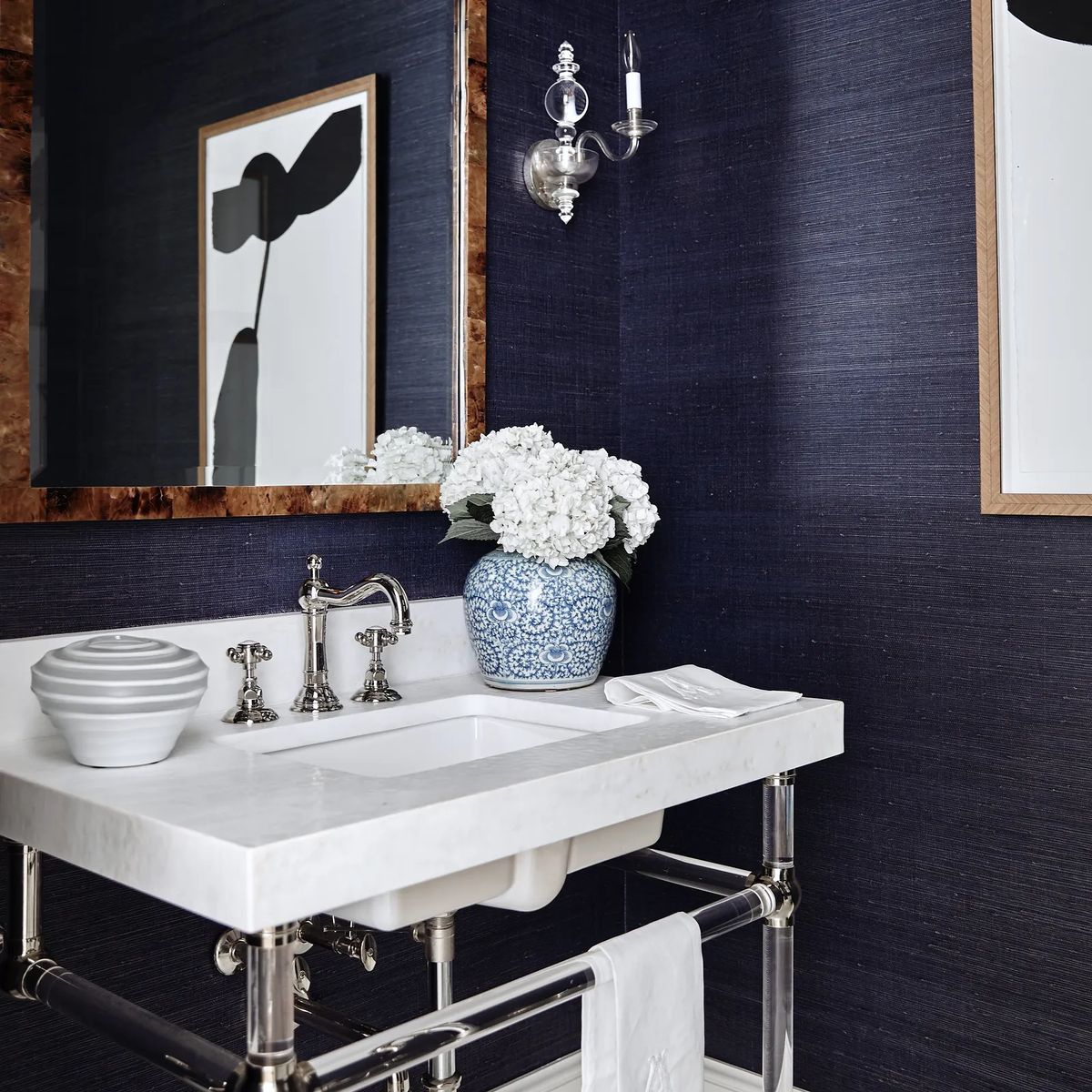 Bathroom with marble sink, chrome fixtures, blue wallpaper, flowers, and decorative bowl