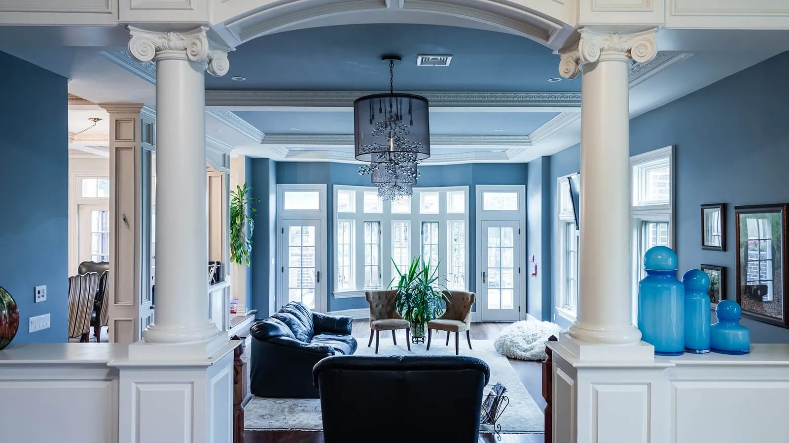 Living room with black sofa, brown armchairs, round coffee table, area rug, tall plant, and blue walls