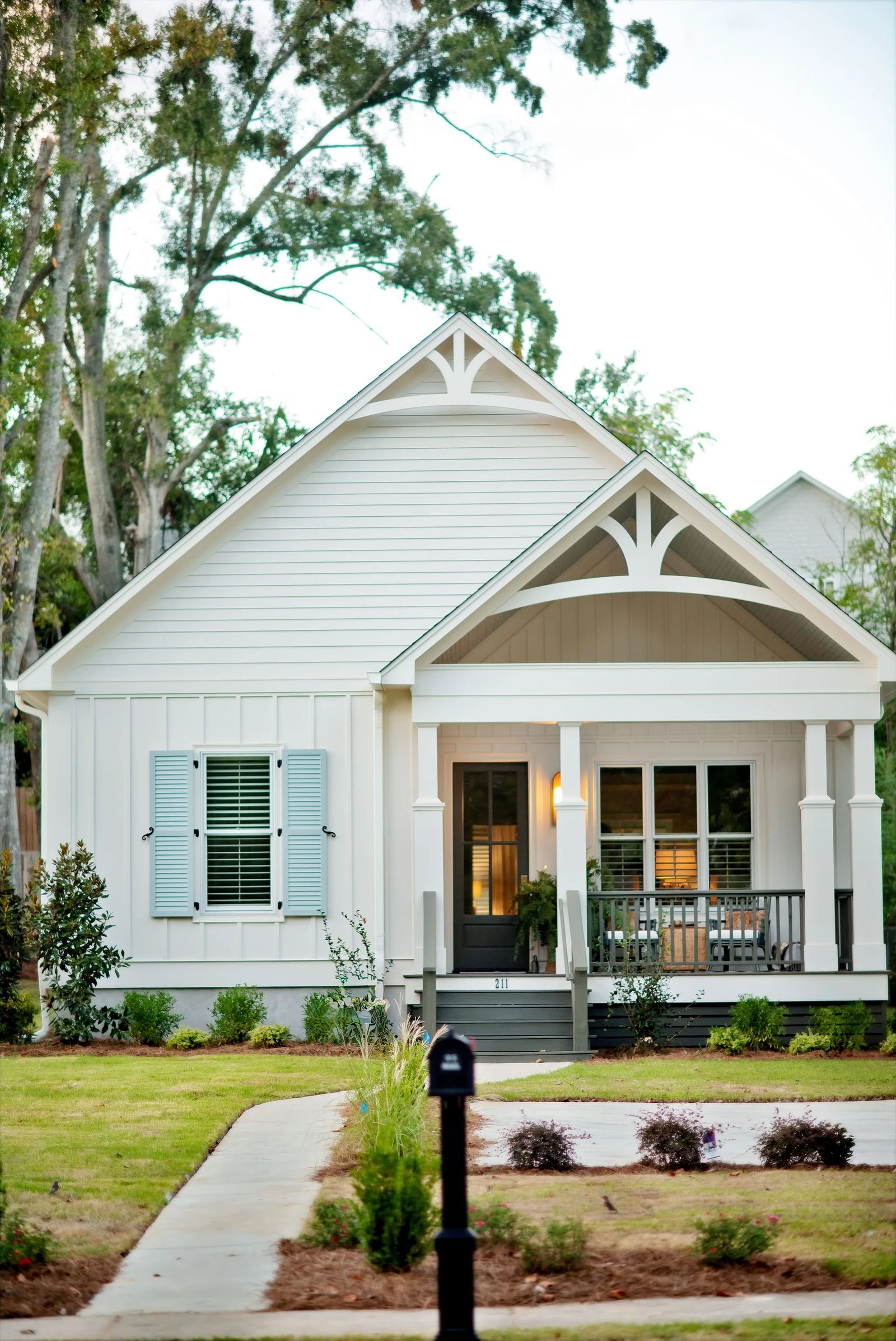 Front exterior of a house with gabled roof, white siding, blue shutters, and a covered porch.