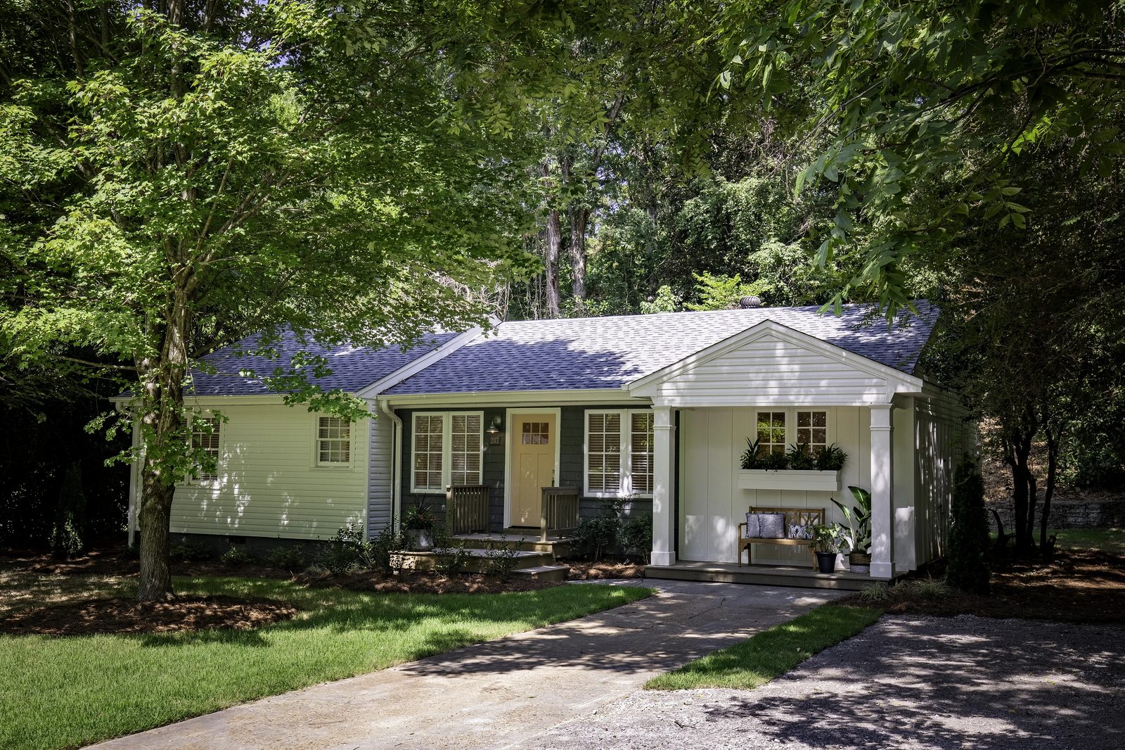 House exterior with gray roof, white siding, front porch, windows, and landscaped yard.