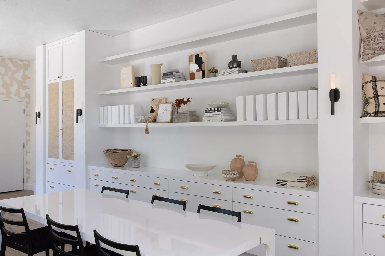 Dining room with white table, black chairs, built-in cabinetry, and decorative items on shelves.