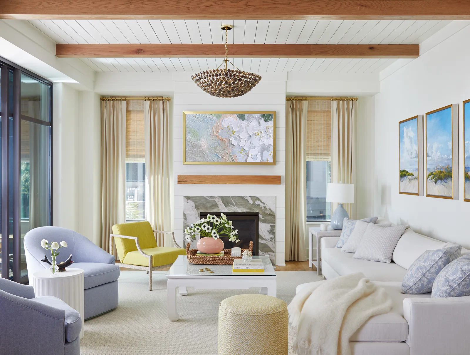 Living room with white sofa, blue armchair, green chair, marble fireplace, and large windows with curtains