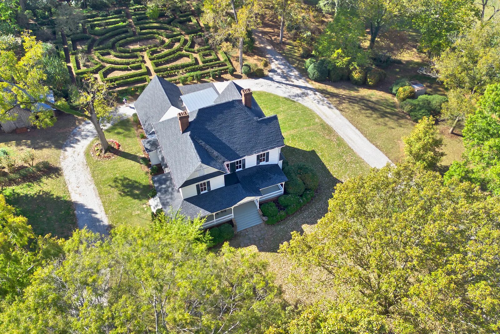 Aerial view of a house with dark gray roof, white siding, and landscaped front yard.