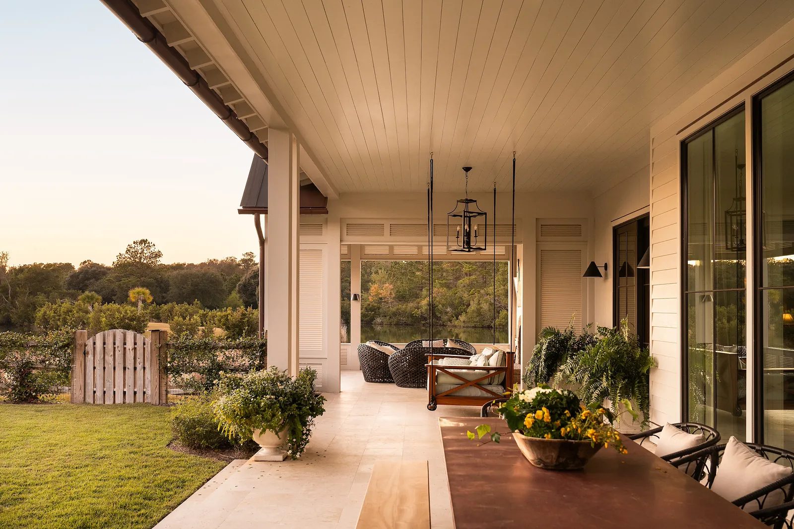 Deck with wooden dining table, wicker chairs, potted plants, and a sliding glass door.