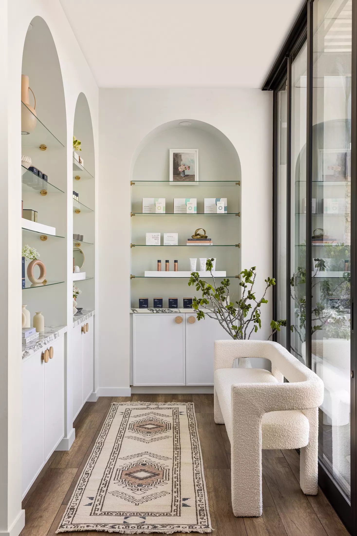 Hallway with built-in shelves, skincare products, bench, and patterned rug with glass panels for natural light