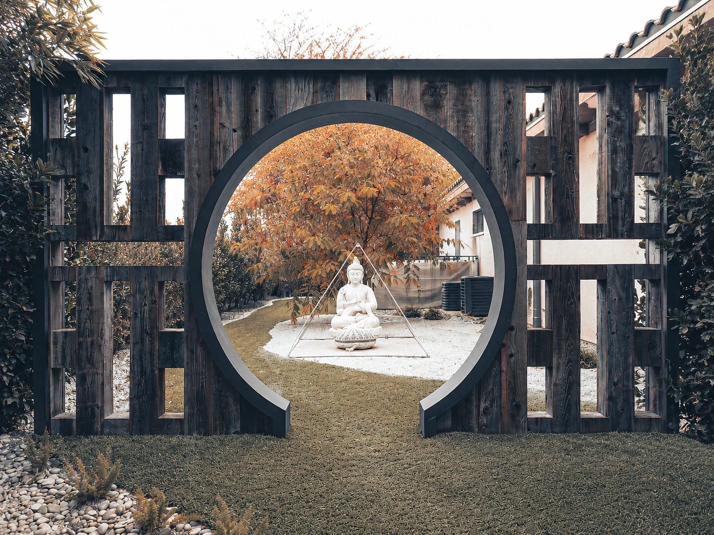Garden with wooden archway, white statue, gravel path, and landscaped greenery.