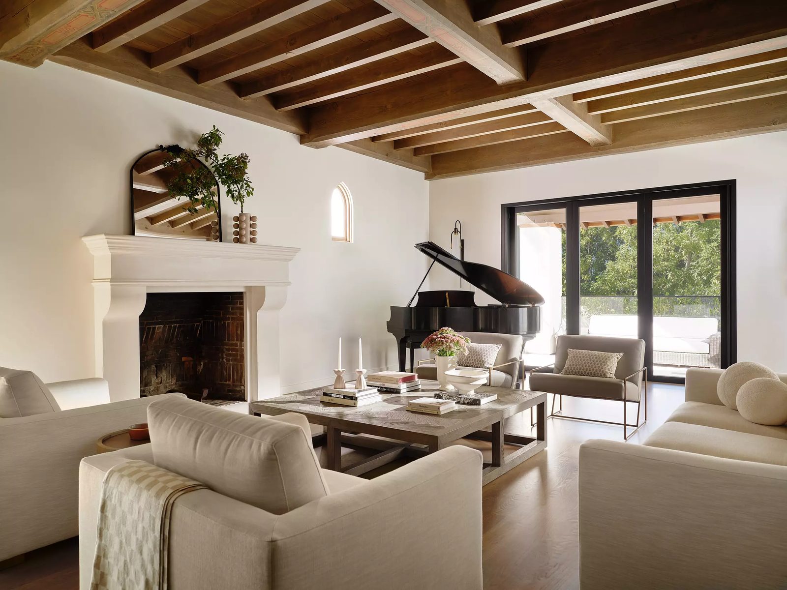 Living room with black grand piano, white sofas, wood coffee table, fireplace, and large glass doors