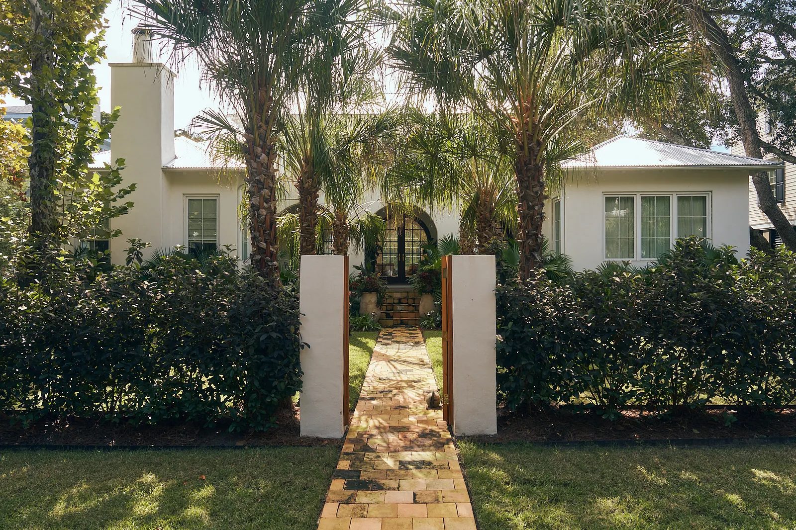 Front exterior of a house with stone pathway, palms, and landscaped garden.