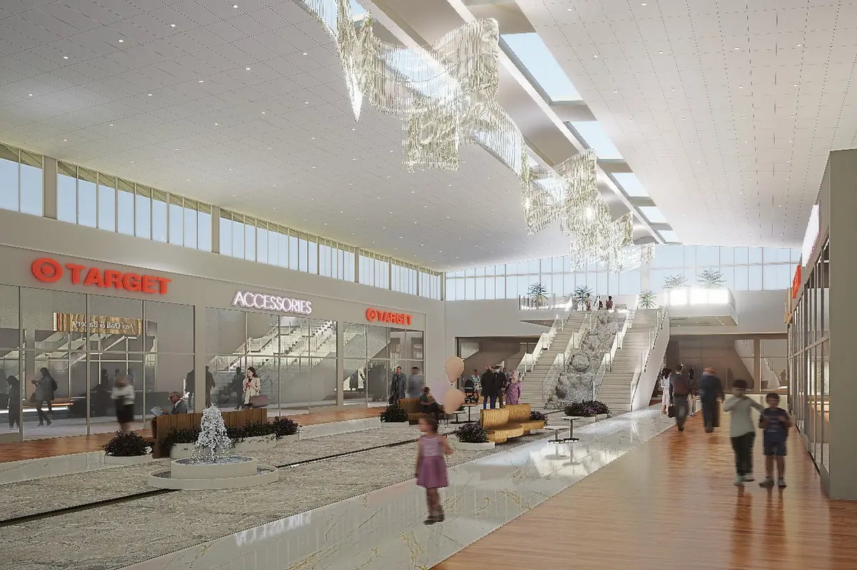 Airport terminal with glass windows, escalators, seating area, retail spaces, and a water feature.