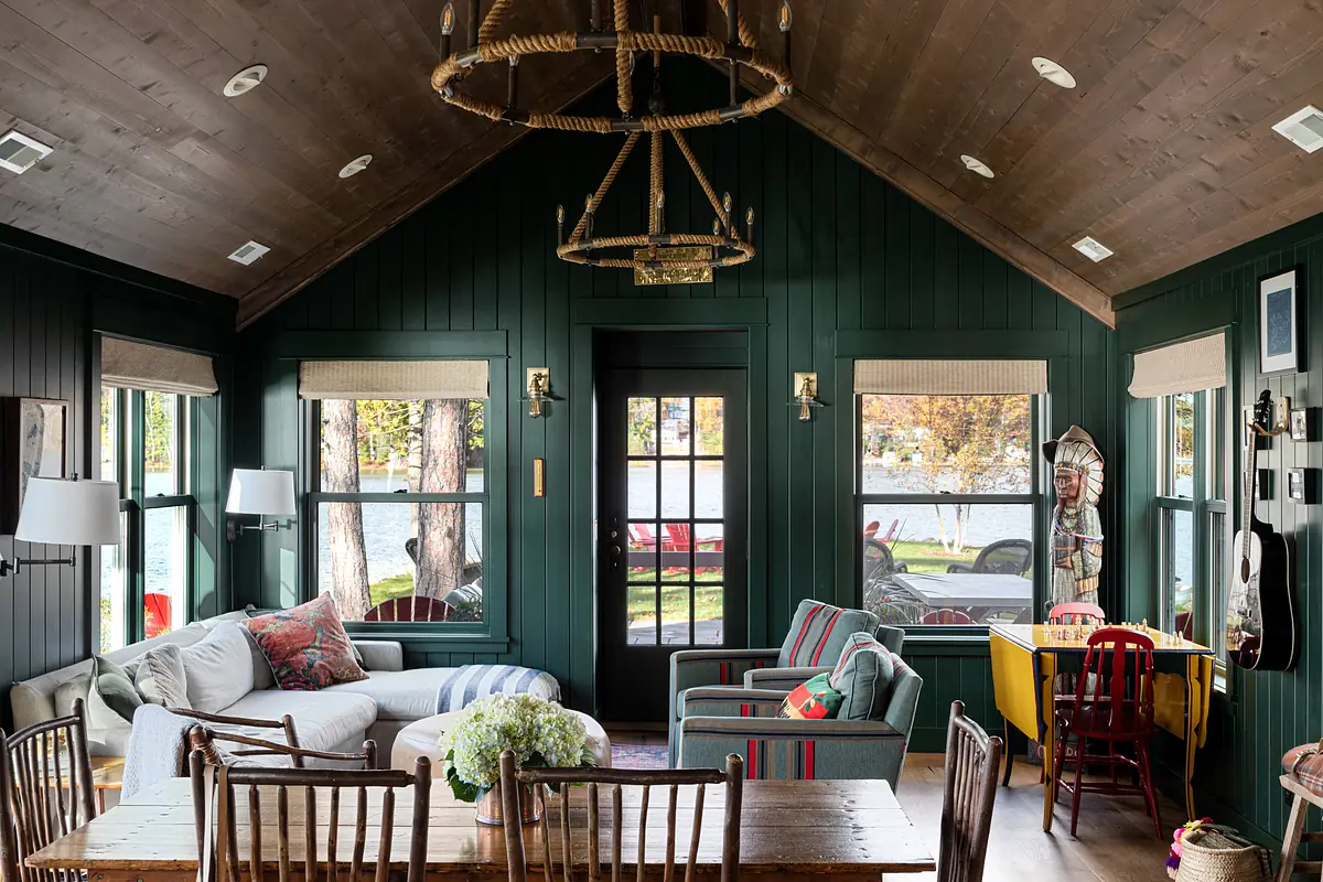 Living room with gray sofa, blue and red armchairs, wooden dining table, striped rug, and green walls