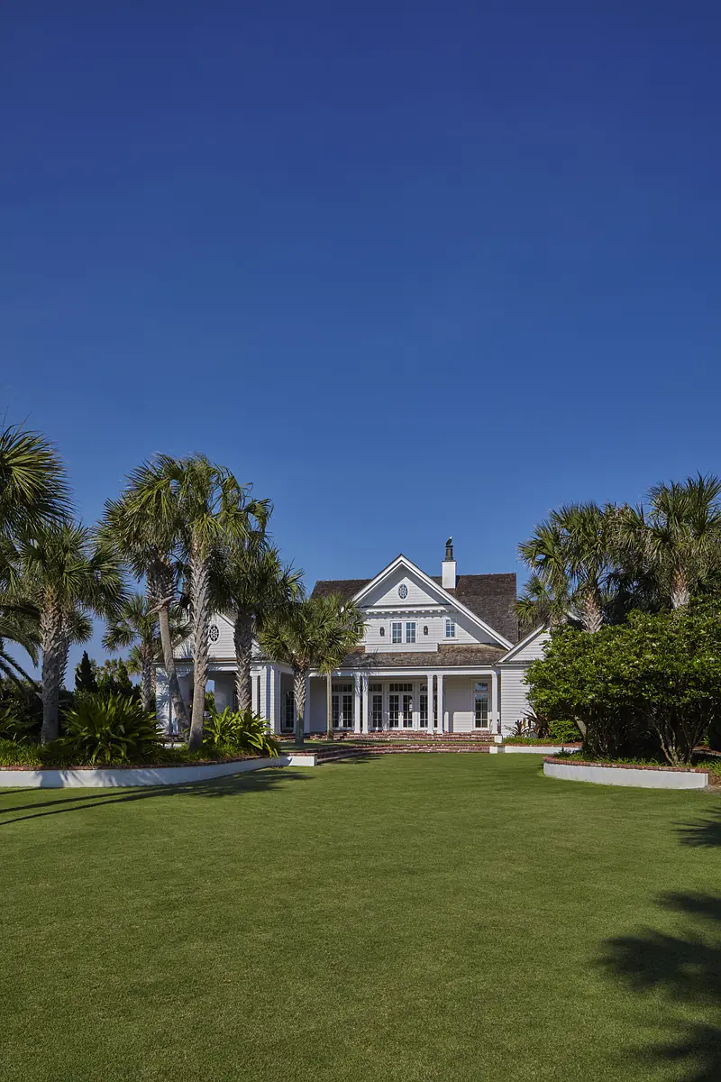 Exterior rear view of a house with lawn, palm trees, and patio area supporting an overhang