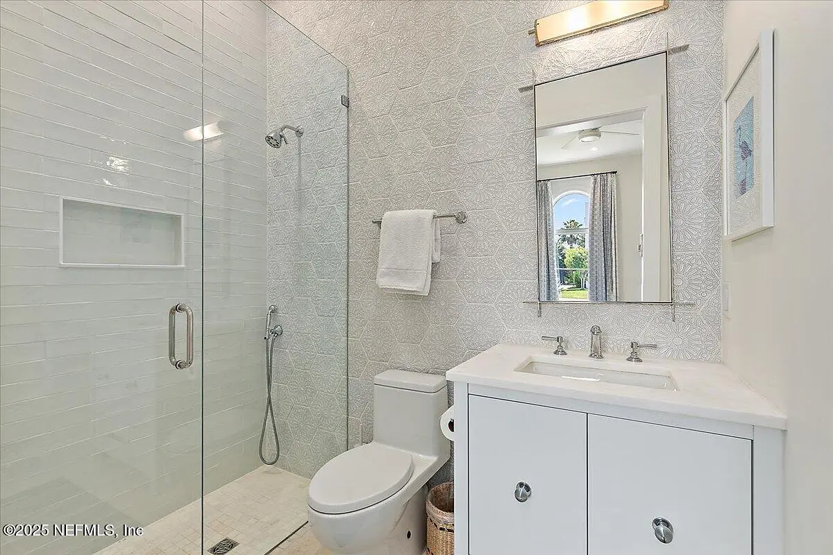 Bathroom with walk-in shower, white toilet, vanity with sink, textured white walls, and tiled floor.