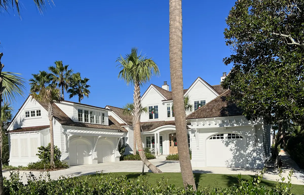 Exterior front view of a white house with gabled roof, landscaped yard, and circular driveway