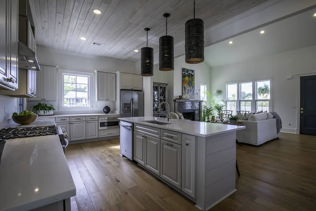 Kitchen with white cabinetry, central island, stainless steel appliances, and wooden floors.