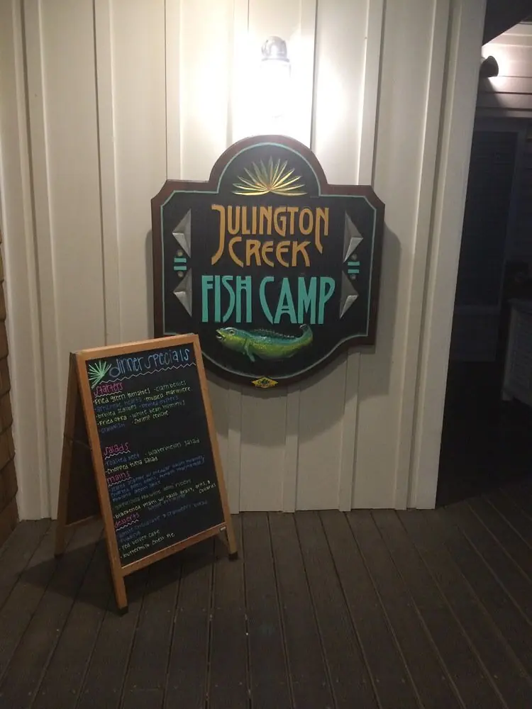 Exterior front with wooden sign for 'Julington Creek Fish Camp' and a chalkboard listing daily specials.