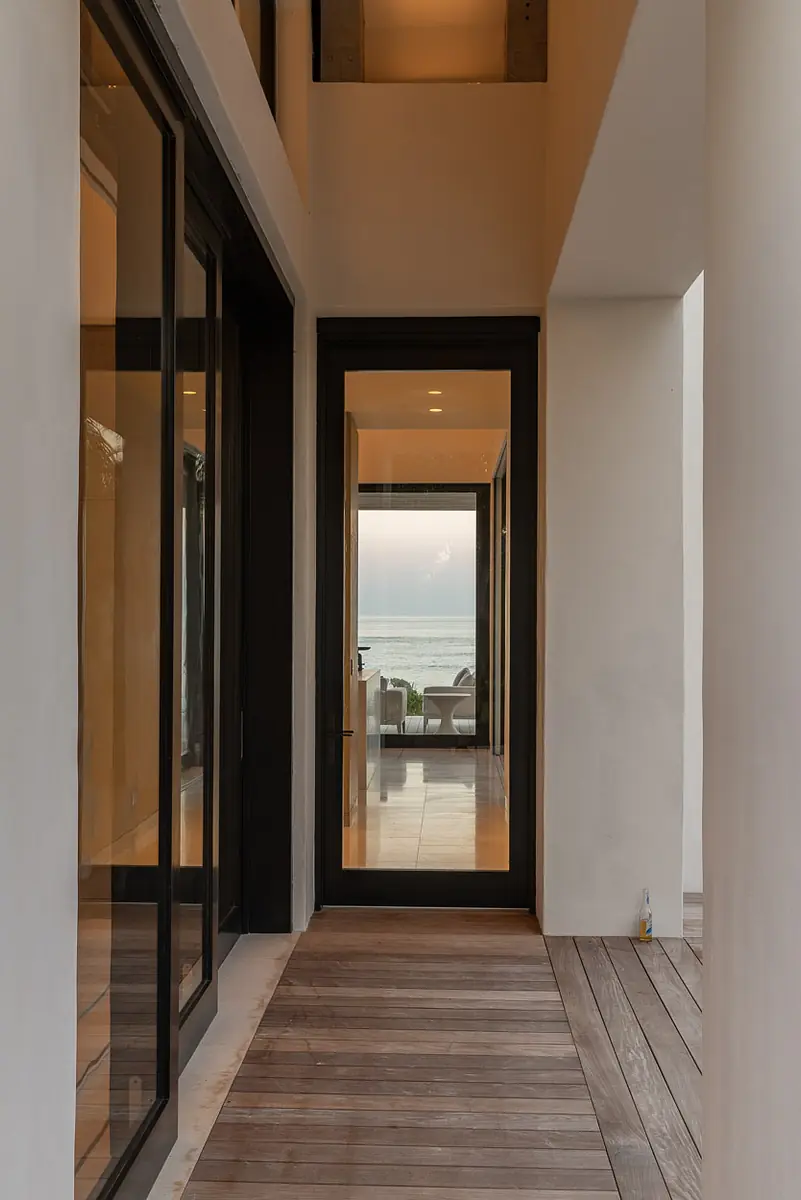 Entryway with large glass doors, light tile floor, and view towards water.