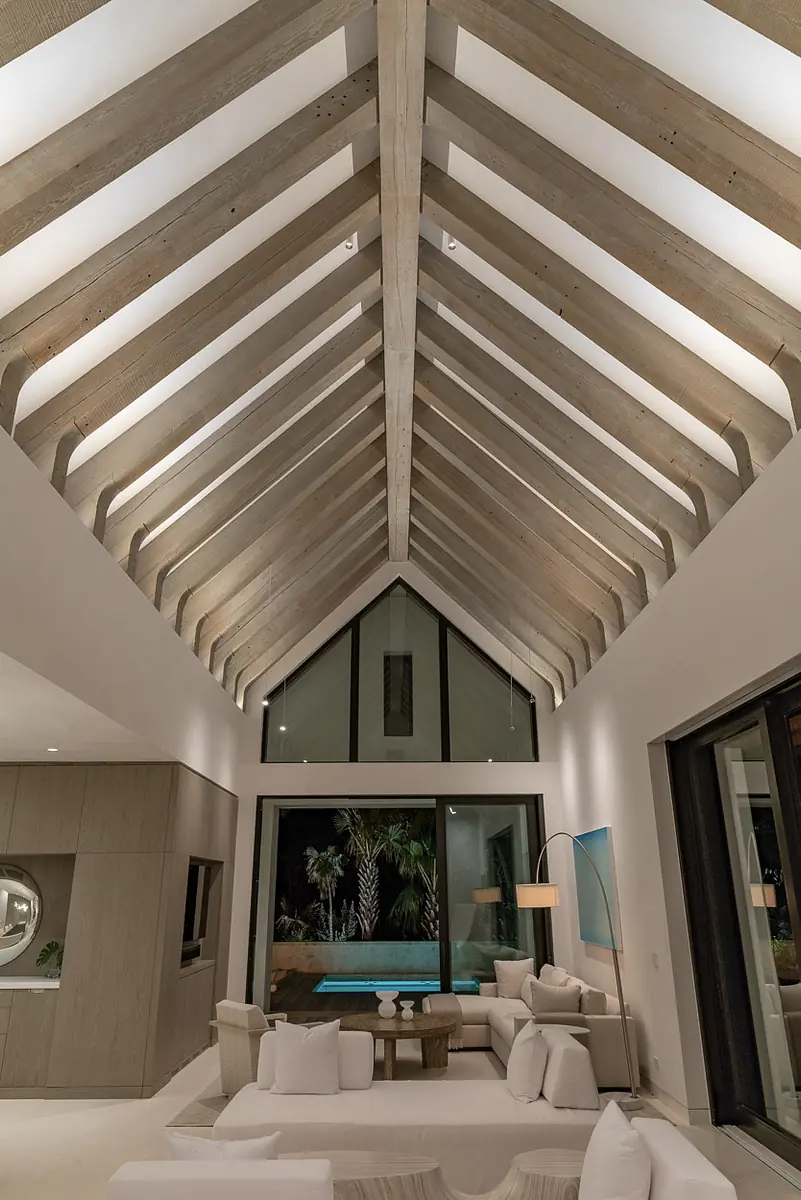 Living room with vaulted ceiling, large windows, sectional sofa, coffee table, and floor lamp.