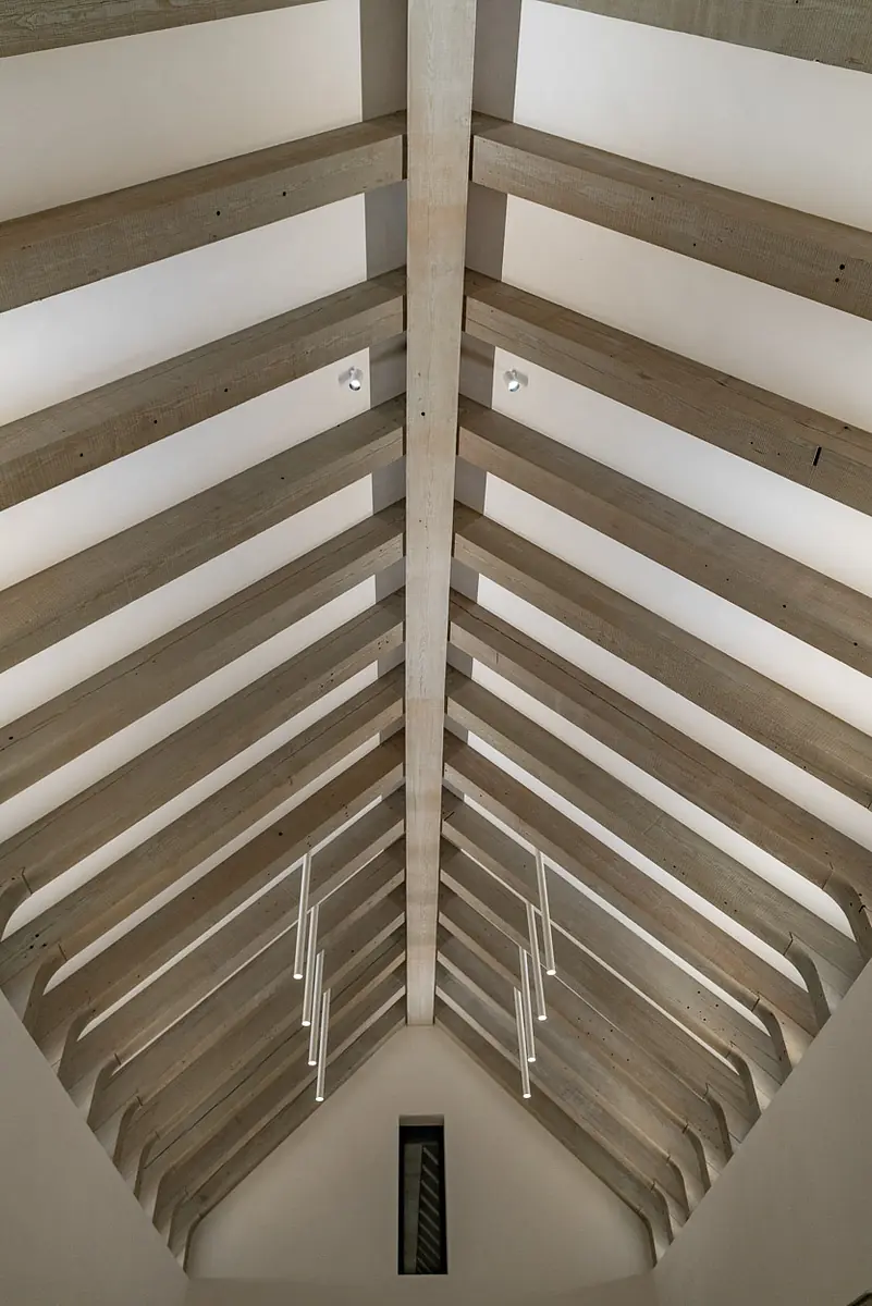 Architectural space with high vaulted ceiling, wooden beams, and pendant light.