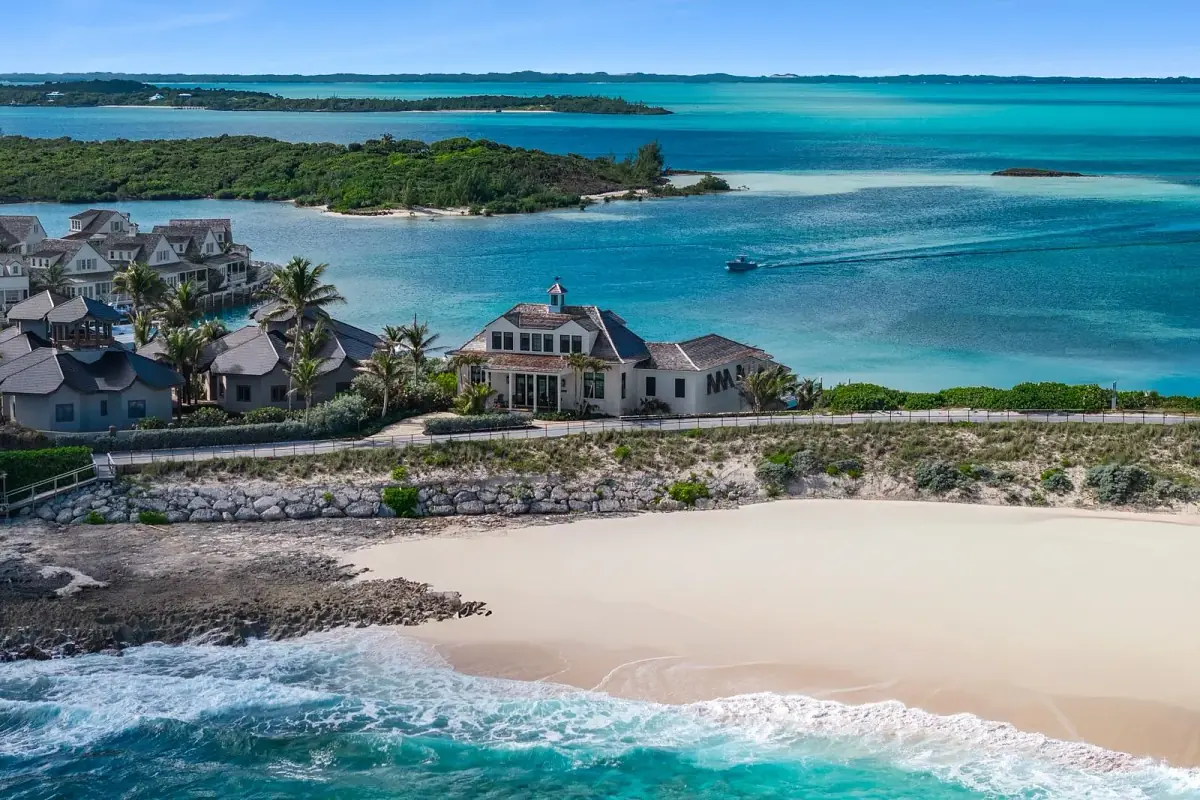 Coastal exterior view of a house with palm trees, beach, and ocean.
