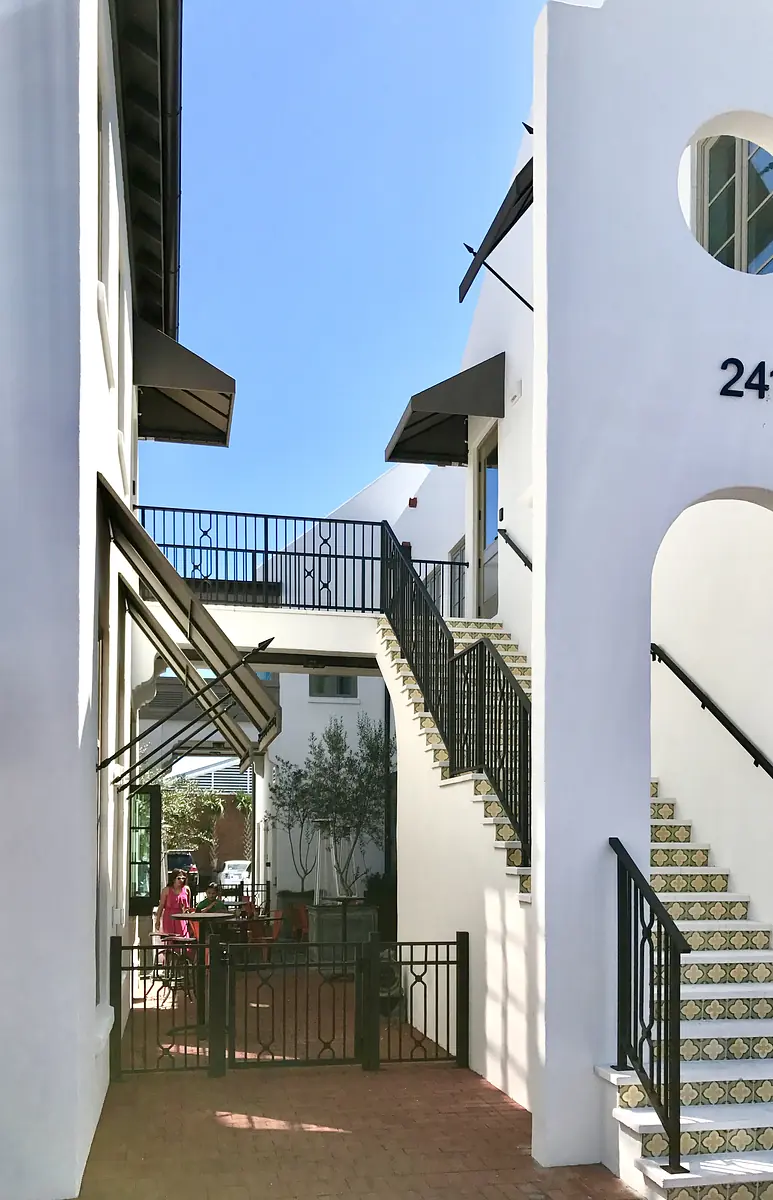 Front exterior view with white stucco, iron railings, tiled stairs, and outdoor seating.