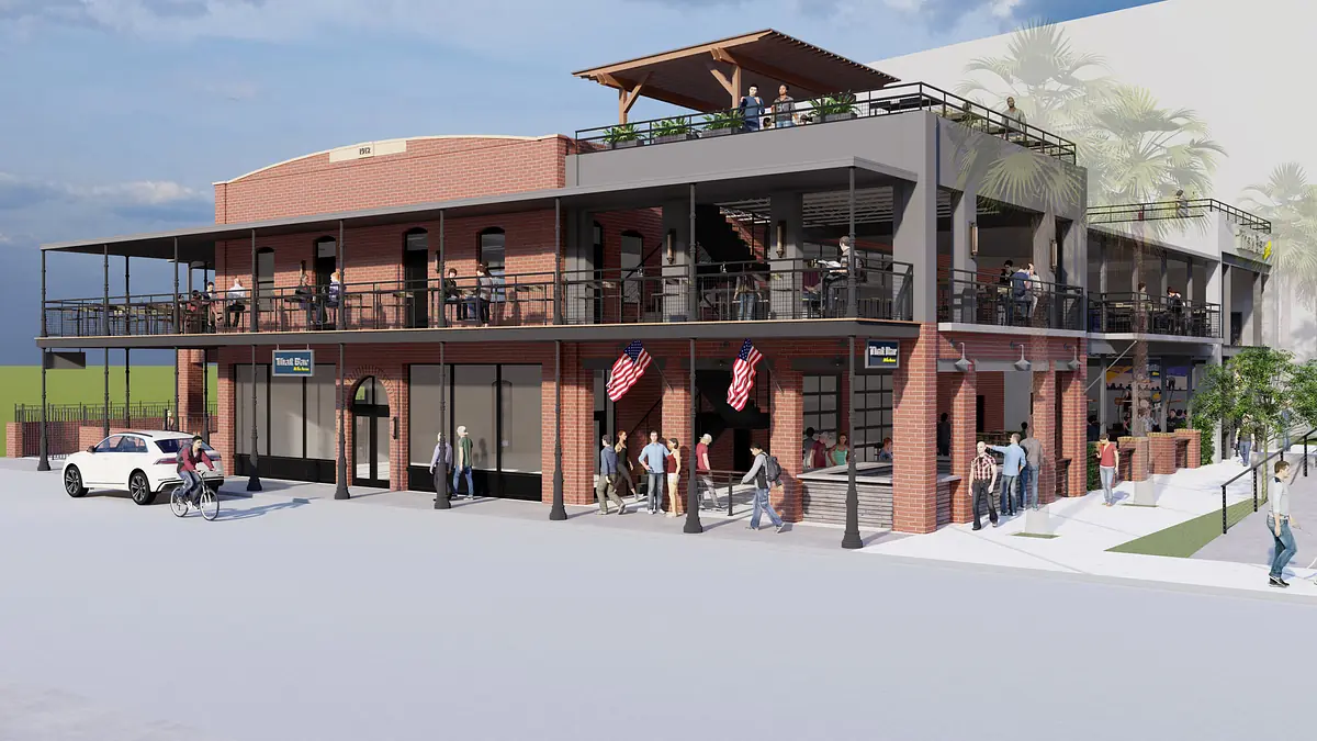 Exterior front view of a two-story brick building with balconies, outdoor seating, and pedestrian activity.