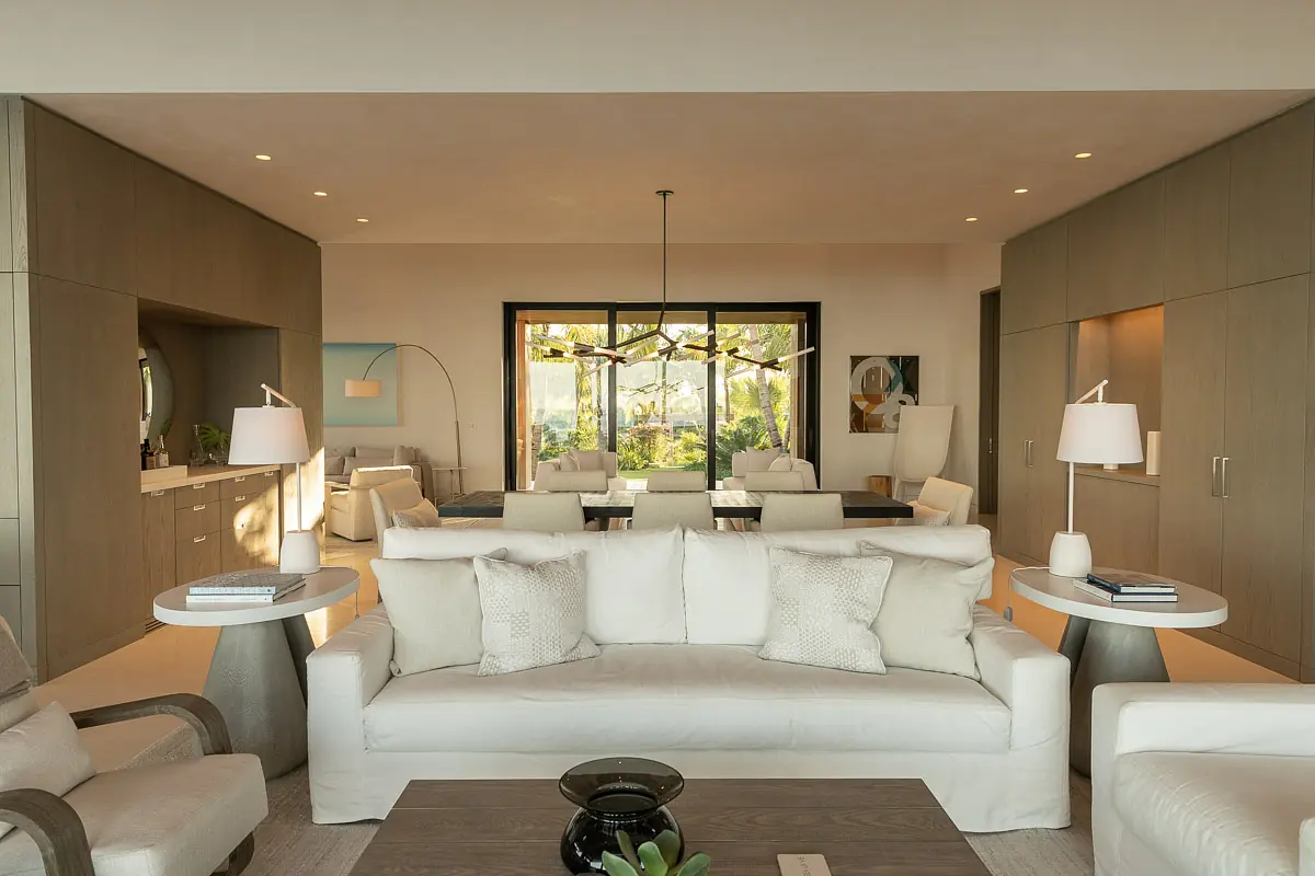 Living room with white sofa, coffee table, side tables, area rug, large windows, and built-in cabinetry.