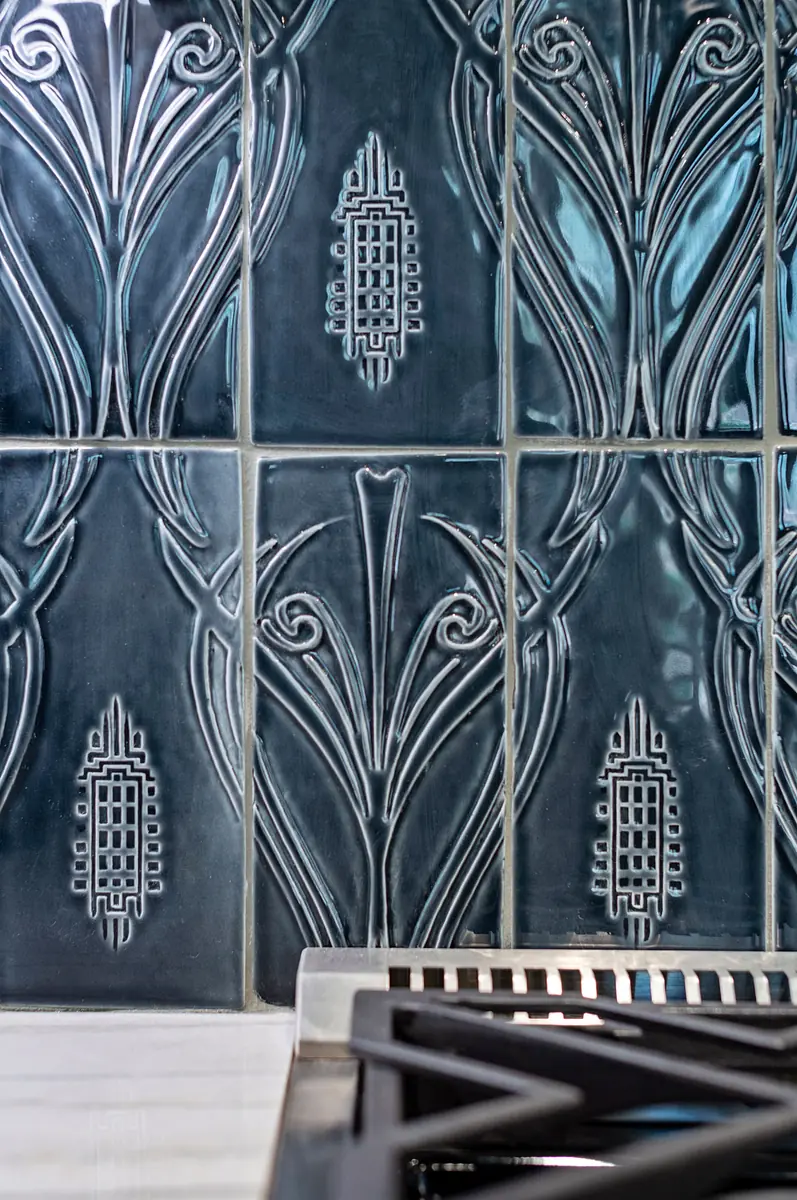 Kitchen with blue embossed tile backsplash and black stovetop.